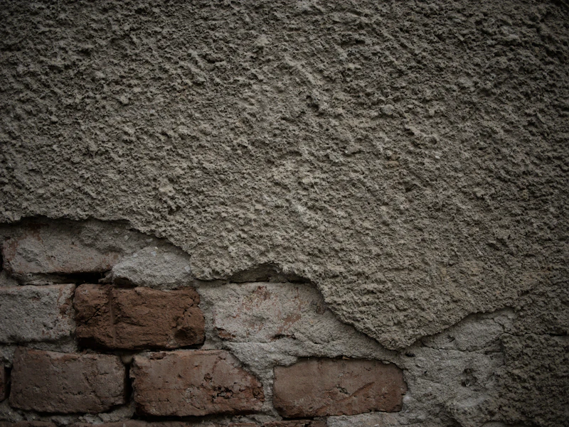 Rough wall with failed render and exposed brick beneath
