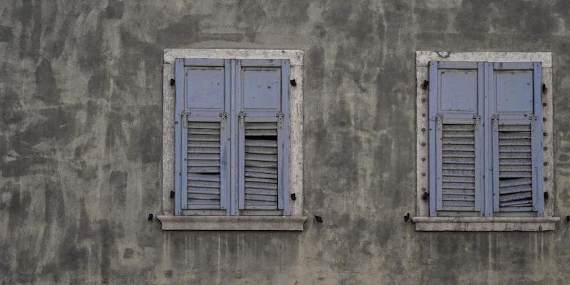 Textured grey rendered wall with painted shutters