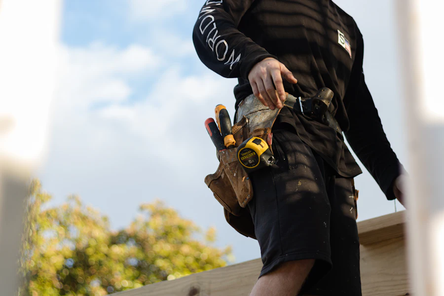 Tradesman wearing a leather tool belt with a tape measure